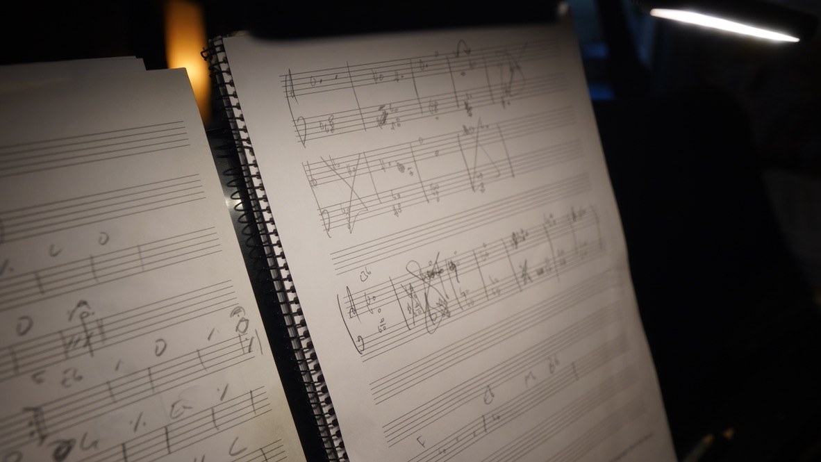 Working manuscript notebooks open on the composer's desk